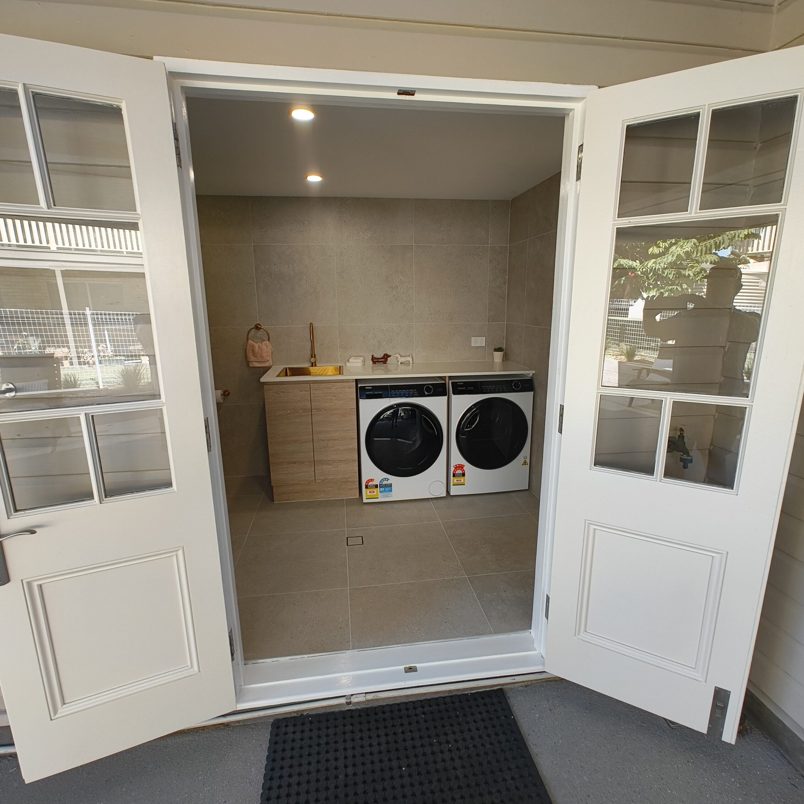 Finished Salisbury laundry conversion with textured cabinetry and stone benchtop