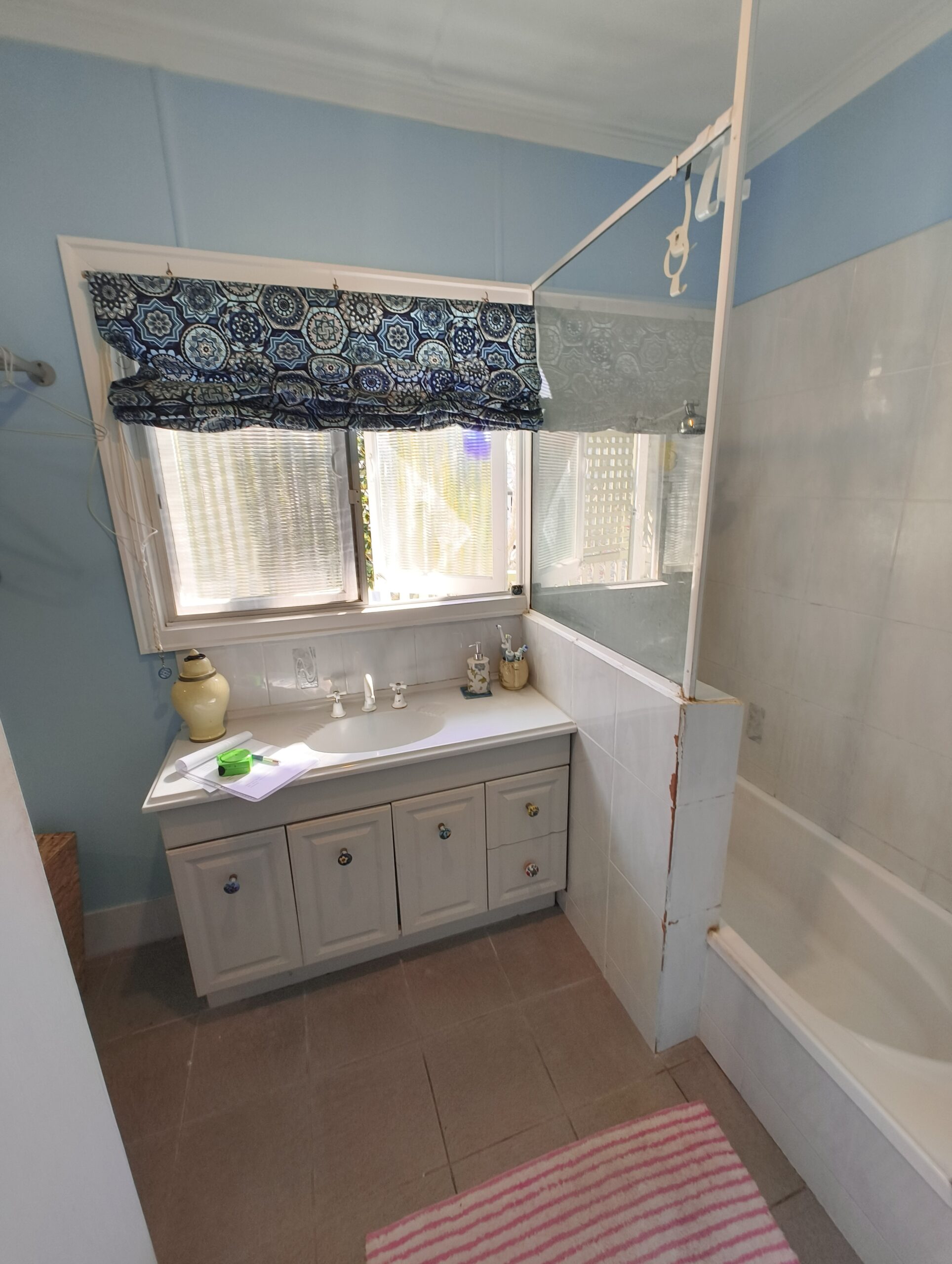 Graceville bathroom before renovation showing the original vanity and bath beneath the window