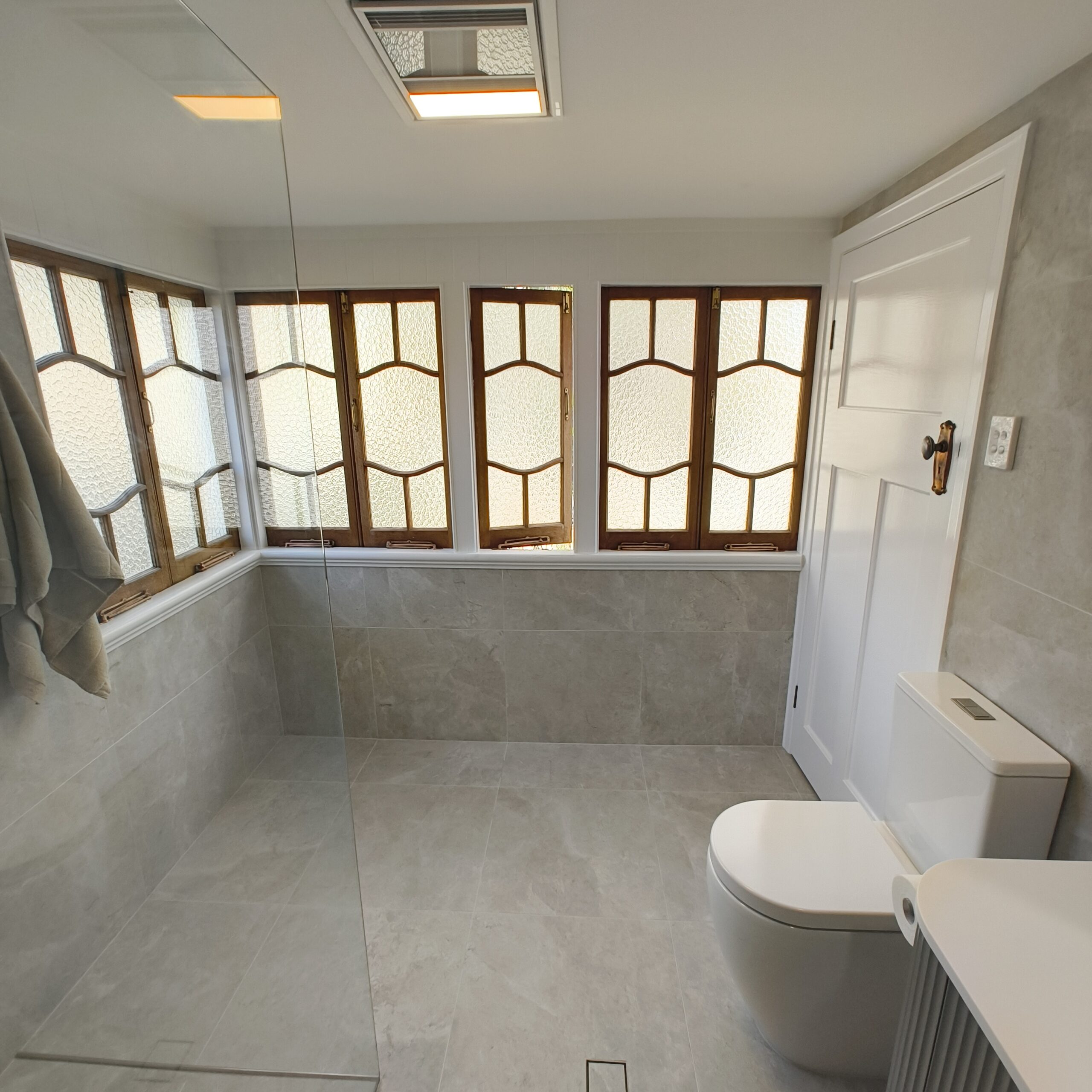 Renovated ensuite in the Woolloongabba Queenslander with stone-look tiles and brushed nickel fittings