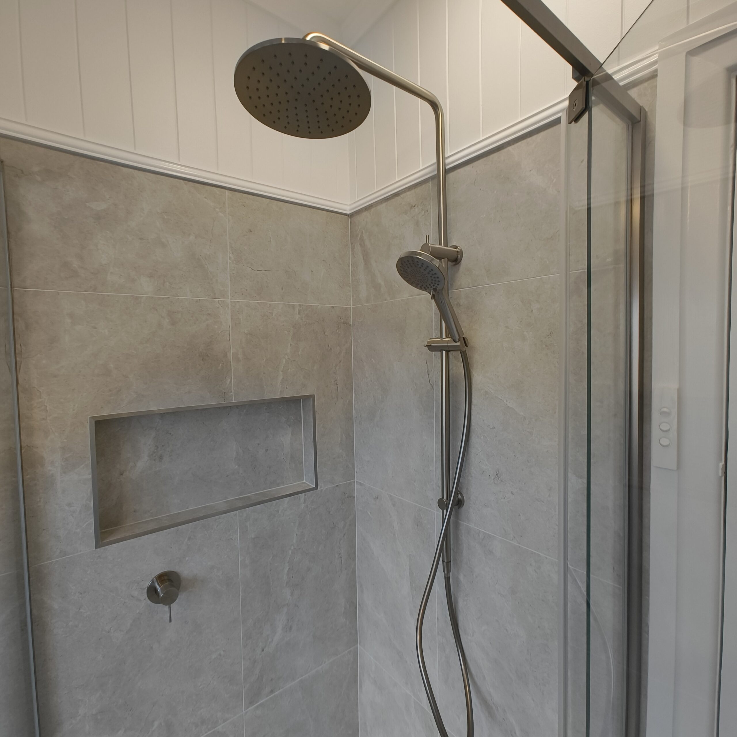 Rain shower and VJ panelling above stone-look tiles in the renovated Woolloongabba main bathroom