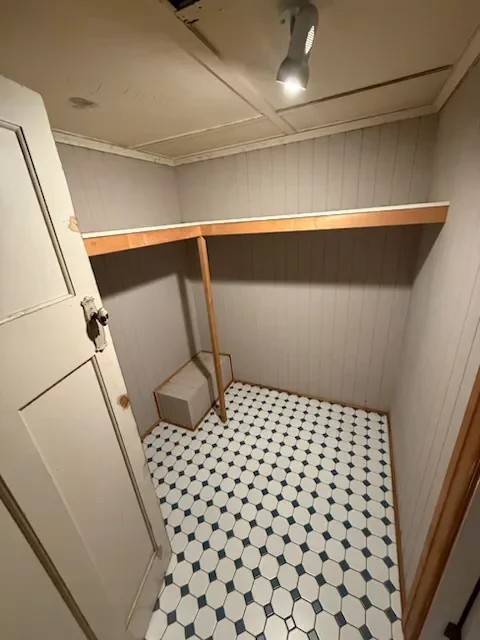 Walk-in robe stripped back before renovation in the Woolloongabba Queenslander, with old timber hanging rail and original floor tiles